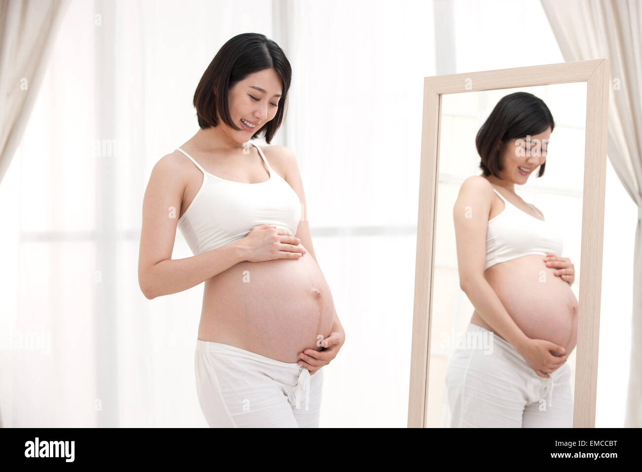 The pregnant woman standing in front of the mirror Stock Photo