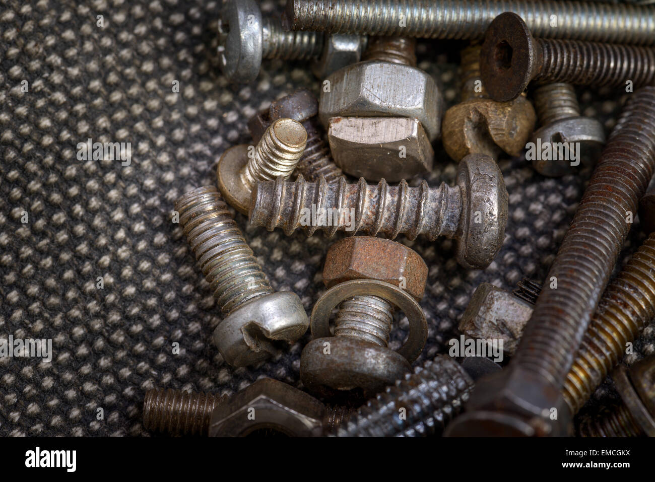 Several old screws on a grey texile background Stock Photo