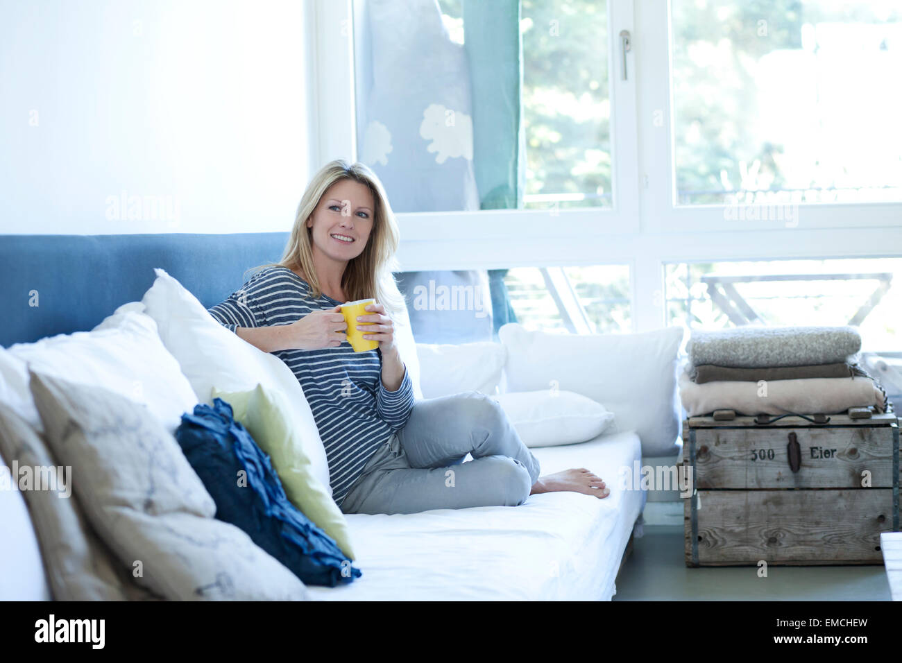 Relaxed woman sitting on couch with cup of coffee Stock Photo - Alamy
