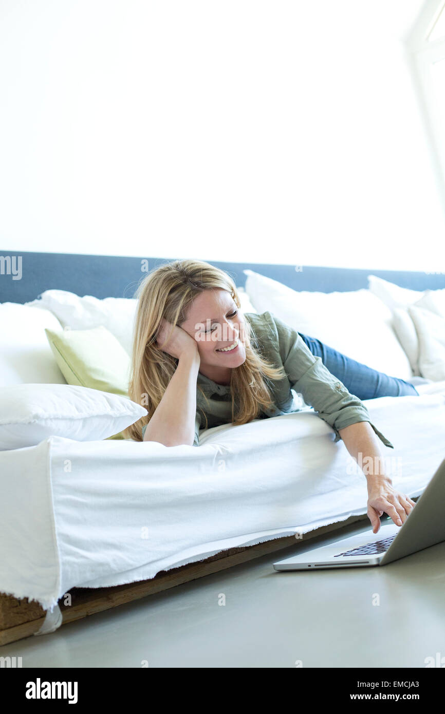Woman relaxing on couch using laptop Stock Photo - Alamy