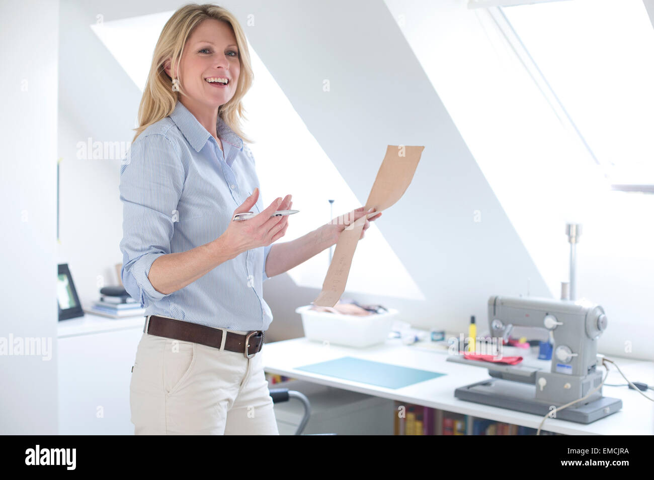 Smiling woman in attic with sewing machine on table Stock Photo Alamy