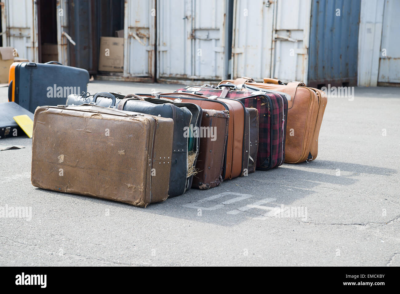 A few very old suitcases clothes are on asphalt. Stock Photo