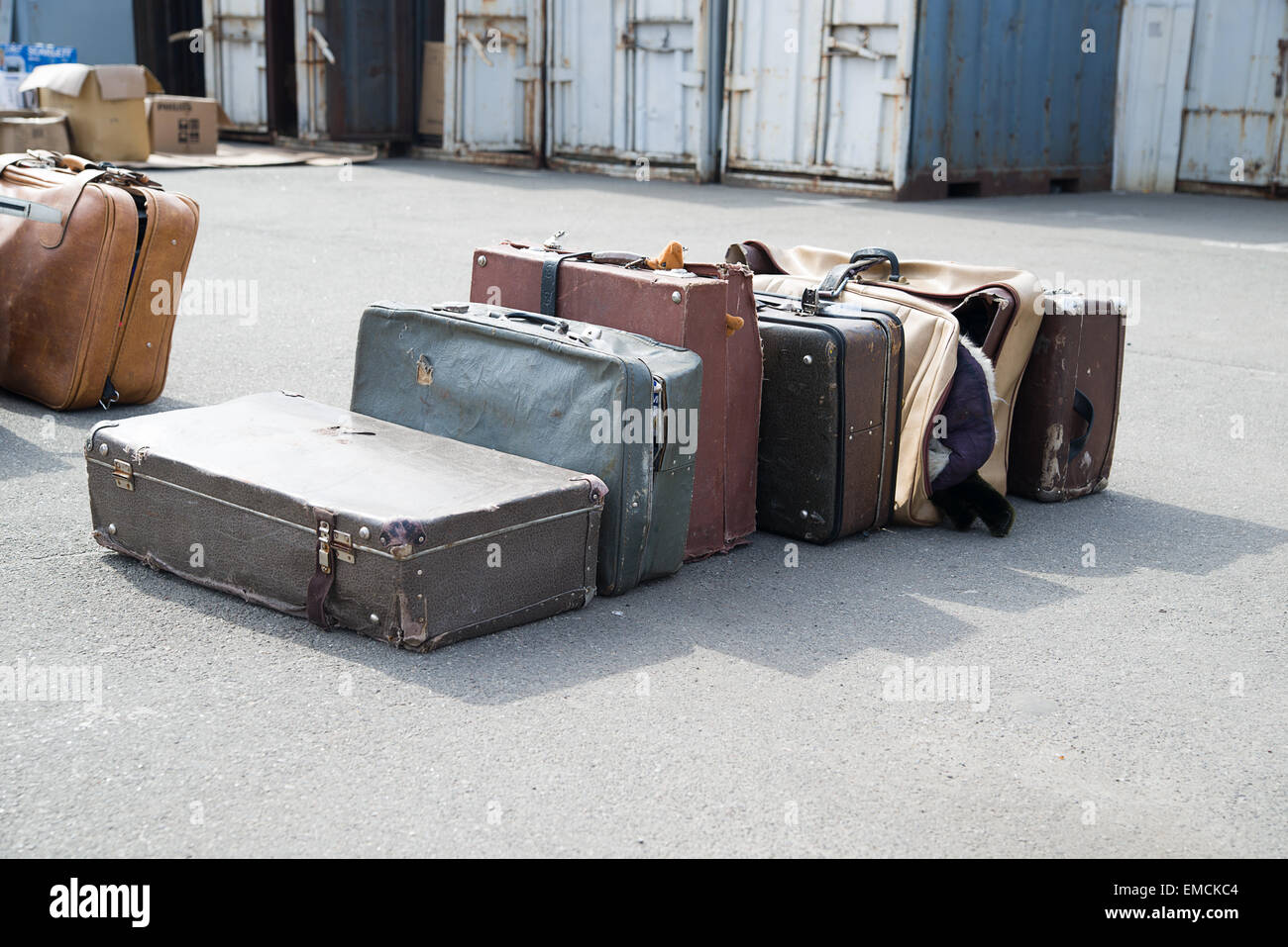 A few very old suitcases clothes are on asphalt. Stock Photo