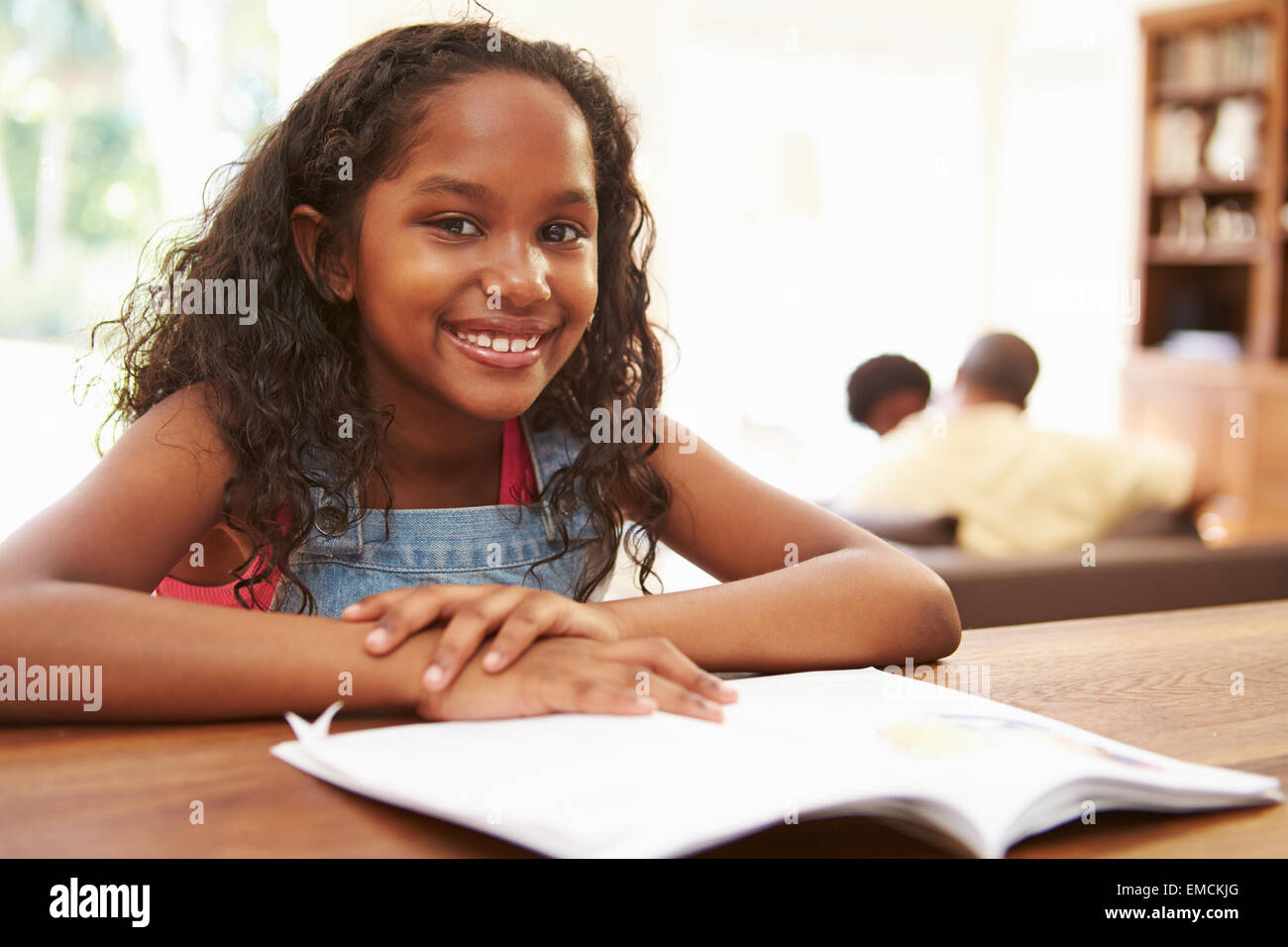 Girl Reading Book For Homework At Table Stock Photo - Alamy