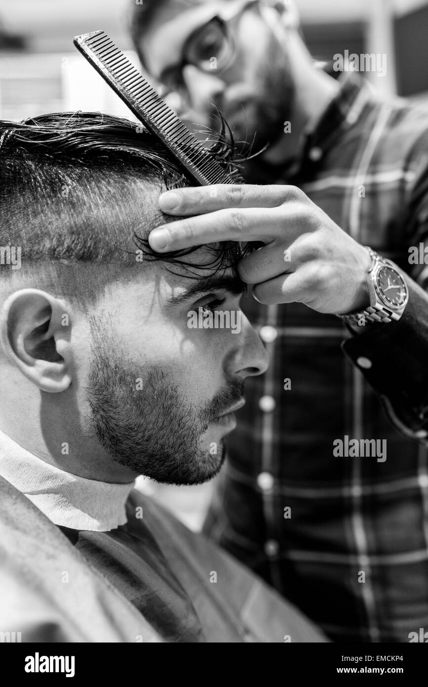 Hairdresser cutting young man's hair in a barbershop Stock Photo