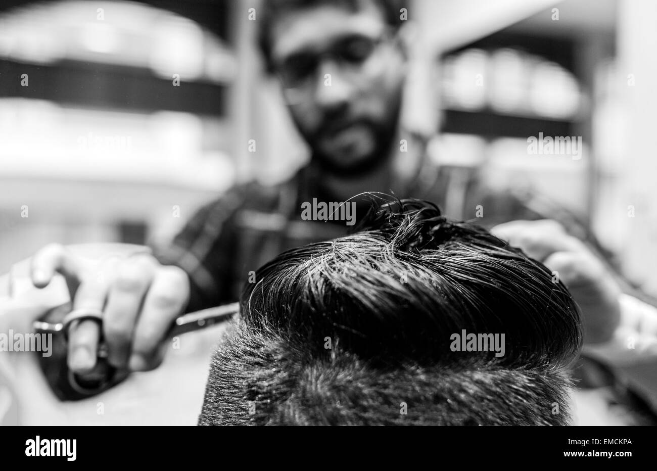 Hairdresser cutting young man's hair in a  barbershop Stock Photo