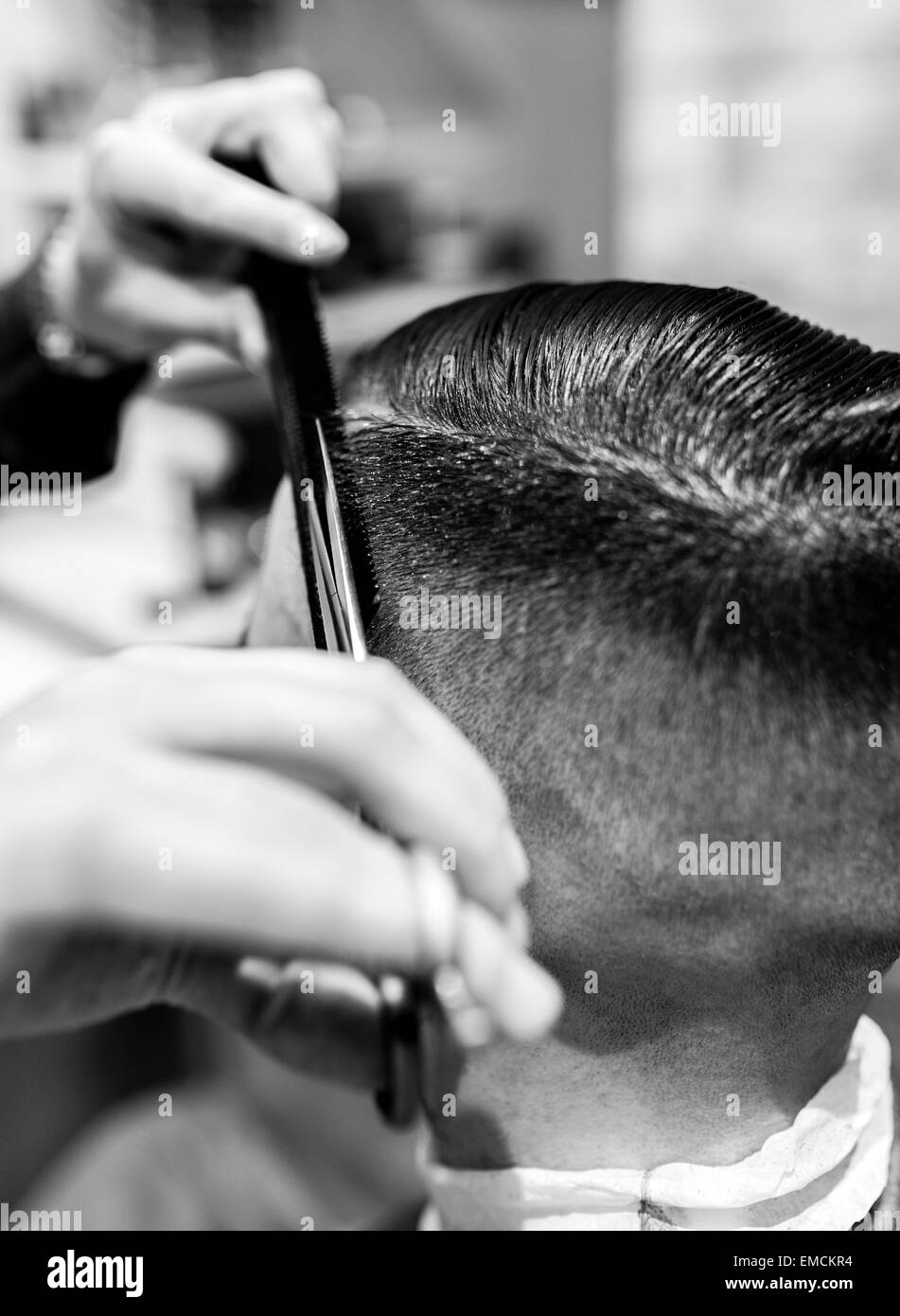 Hairdresser cutting young man's hair in a barbershop Stock Photo