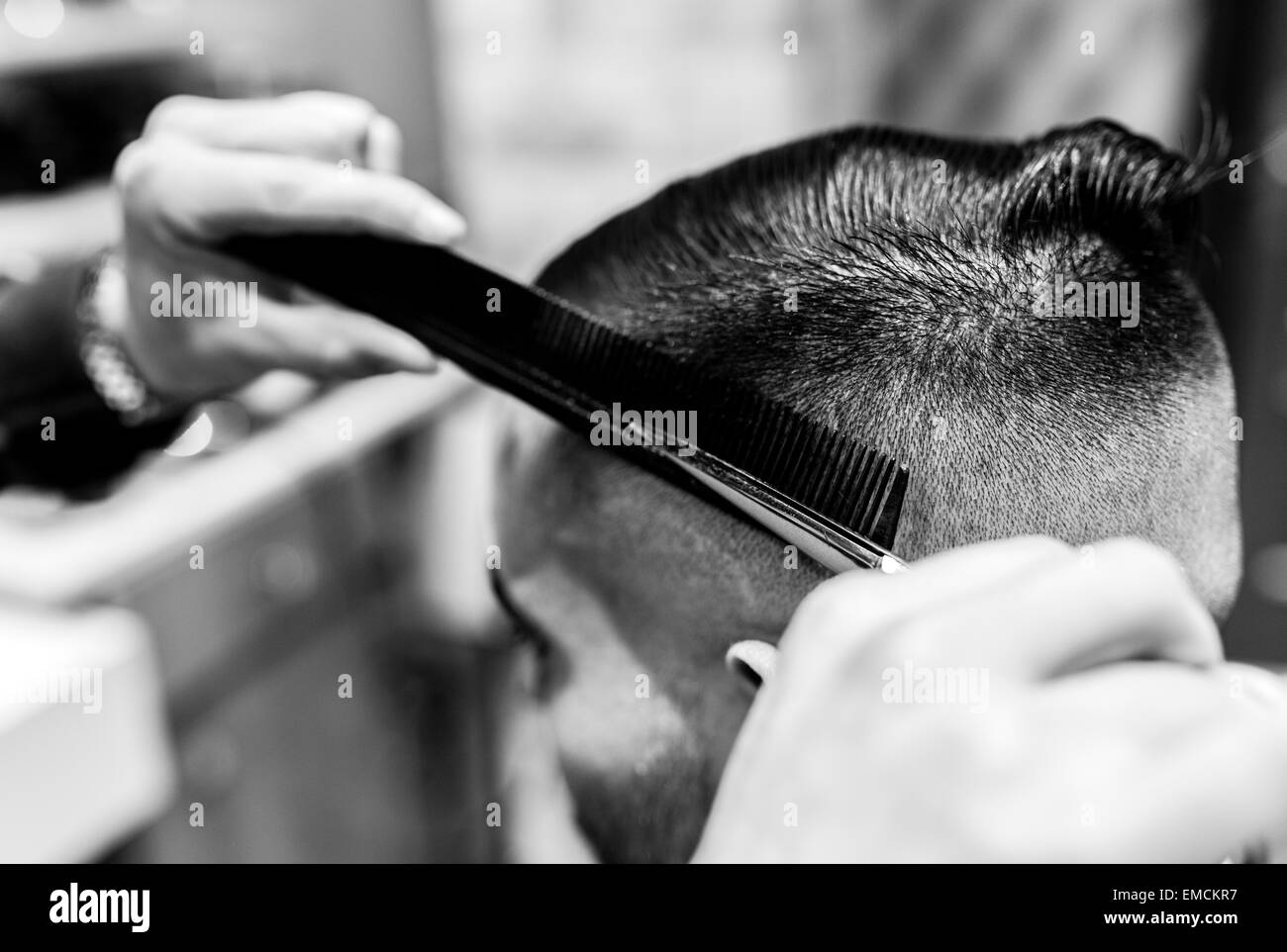 Hairdresser cutting young man's hair in a barbershop Stock Photo