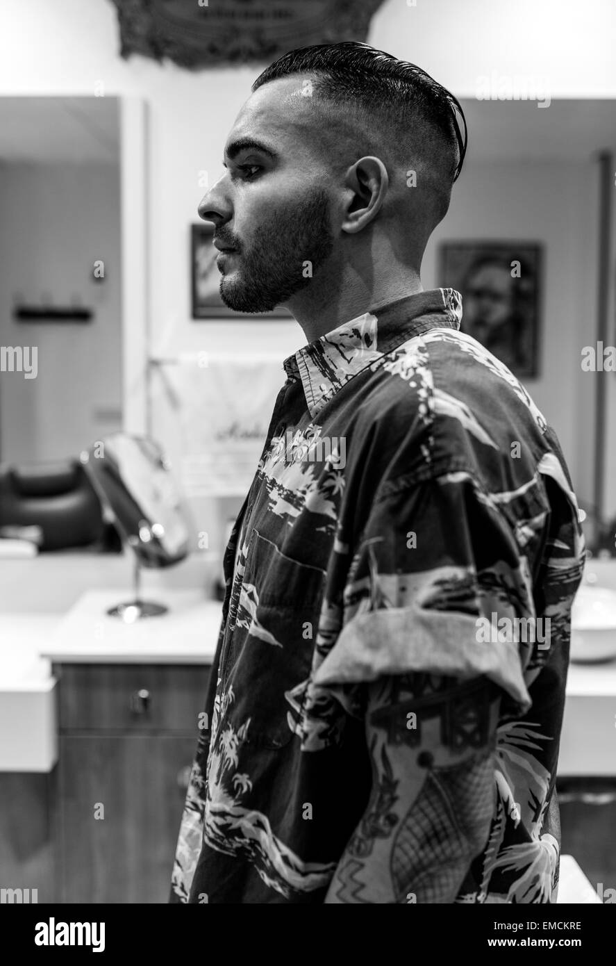 Young man with tattoos on his arm and shaved head in a barbershop Stock Photo