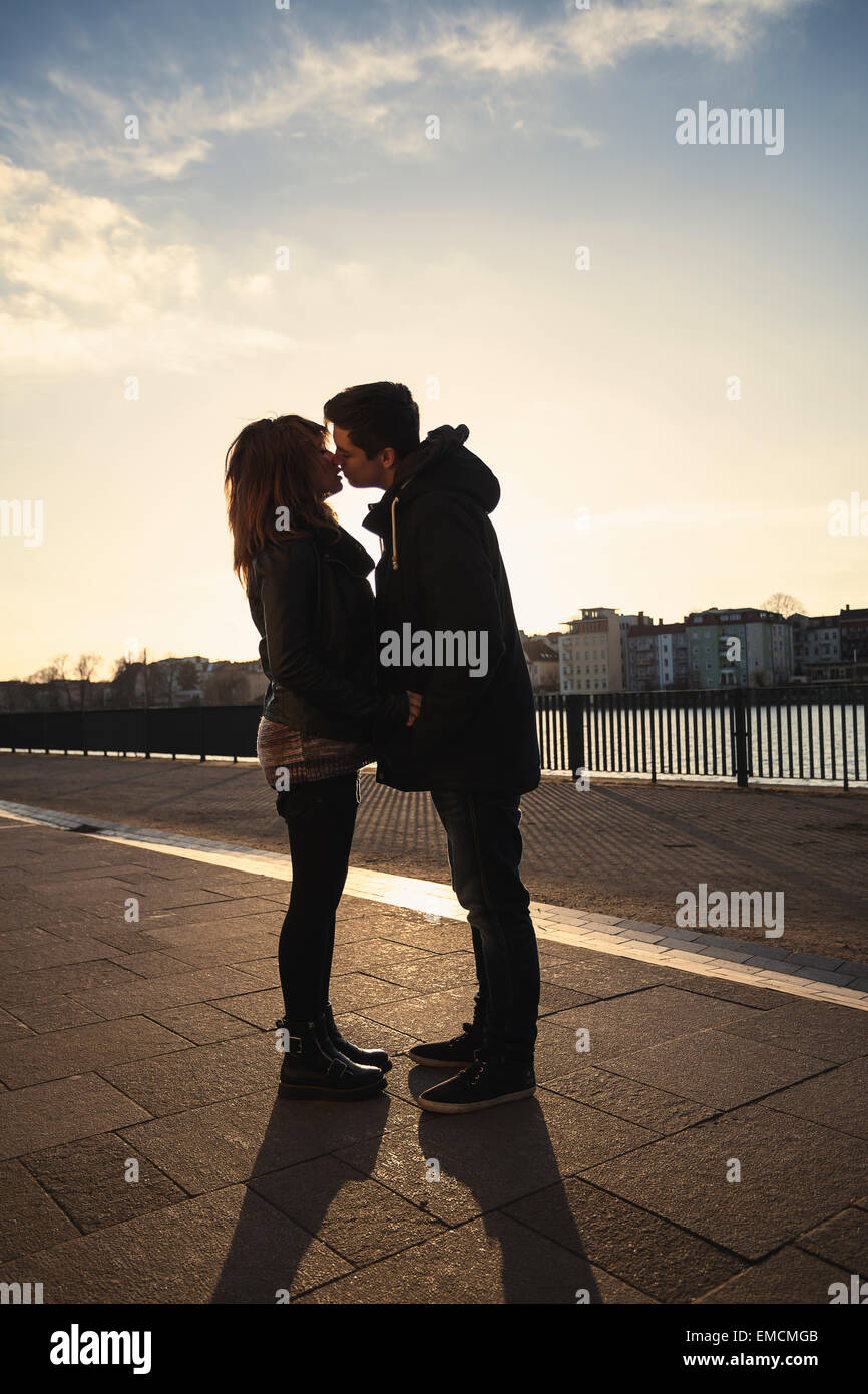 Germany, Berlin, teenage couple kissing on a promenade along a lake