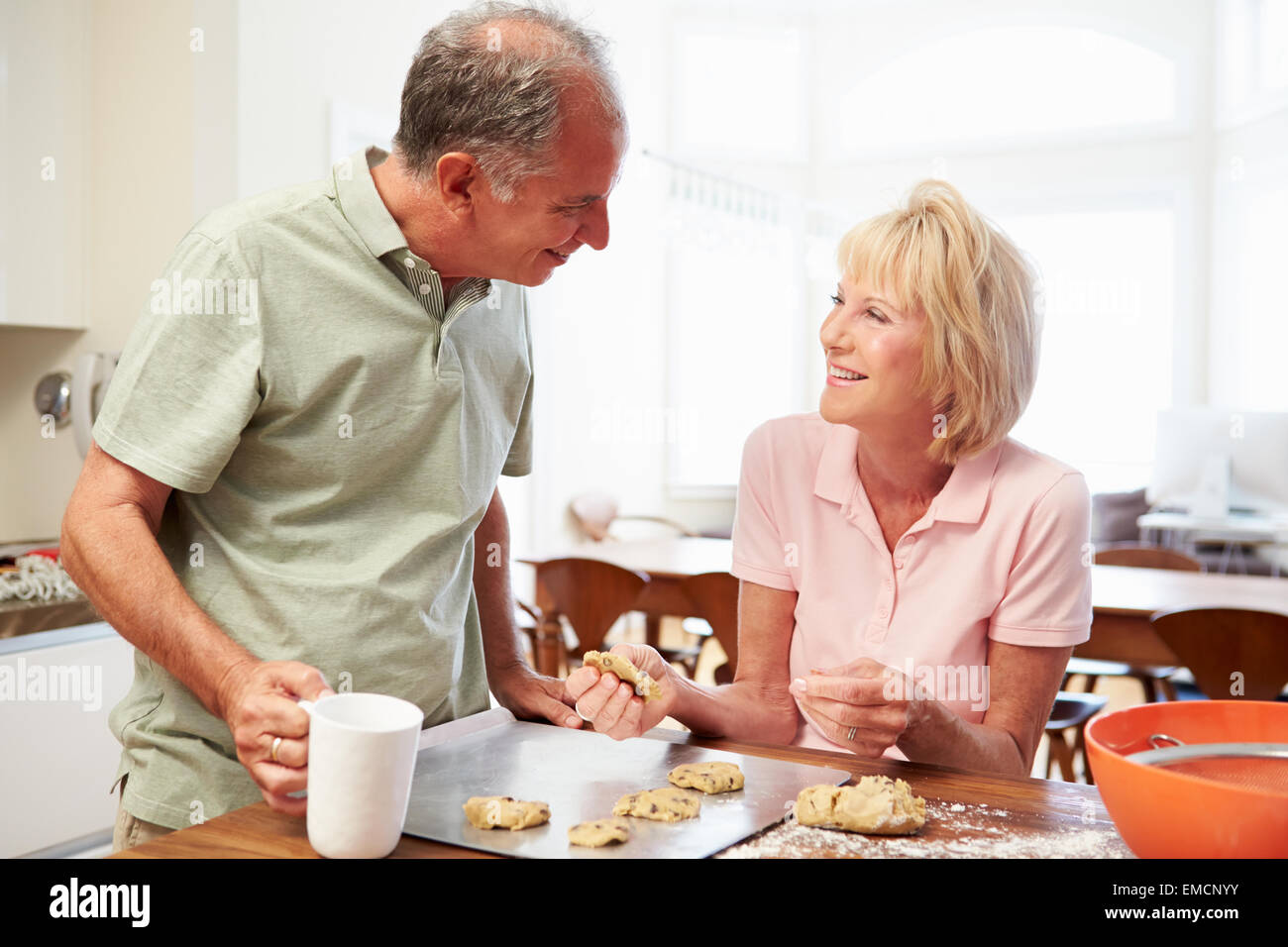 Senior Woman With Husband Baking Cookies In Kitchen Stock Photo
