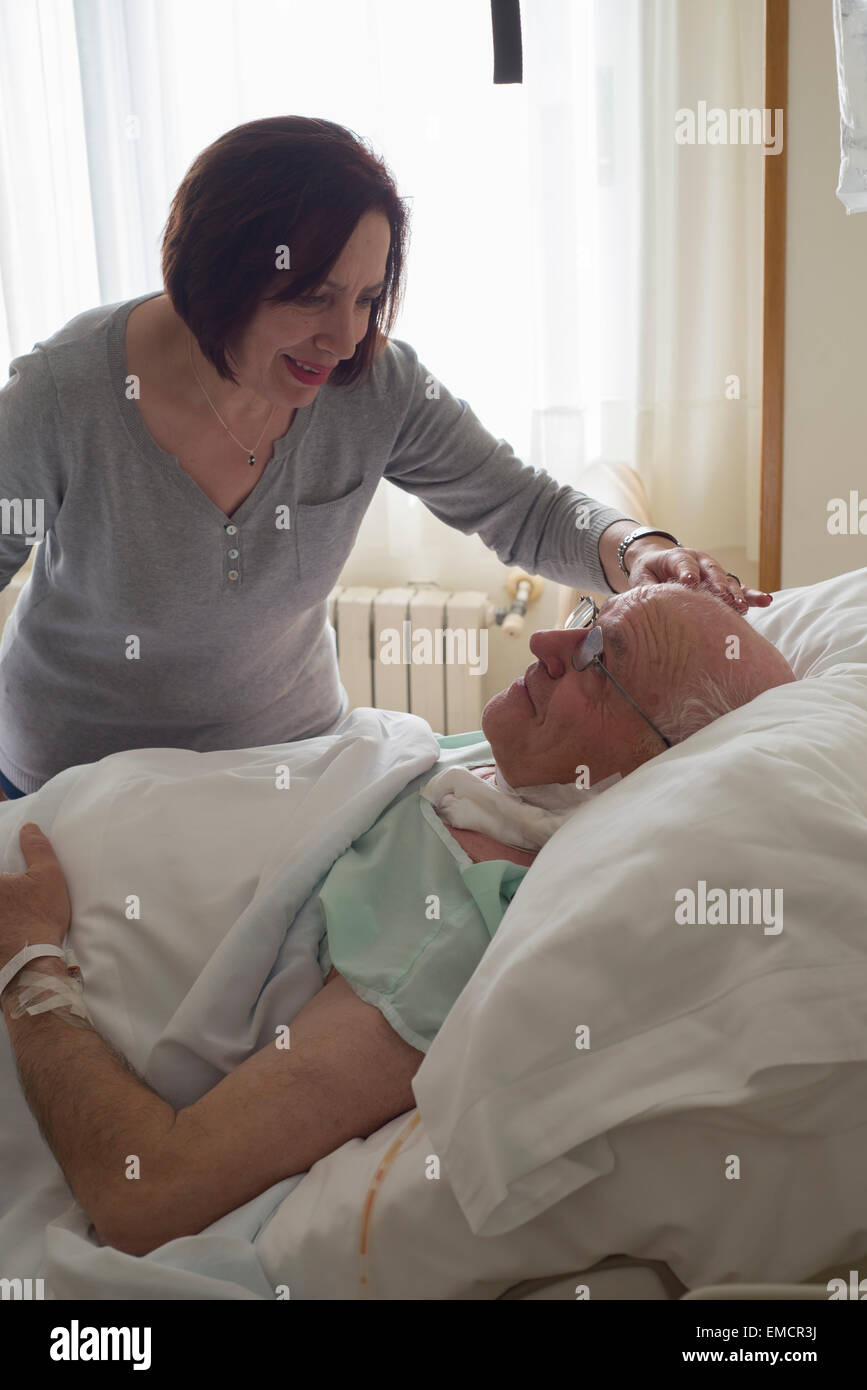 Senior woman caring for husband in hospital recovering after surgery ...