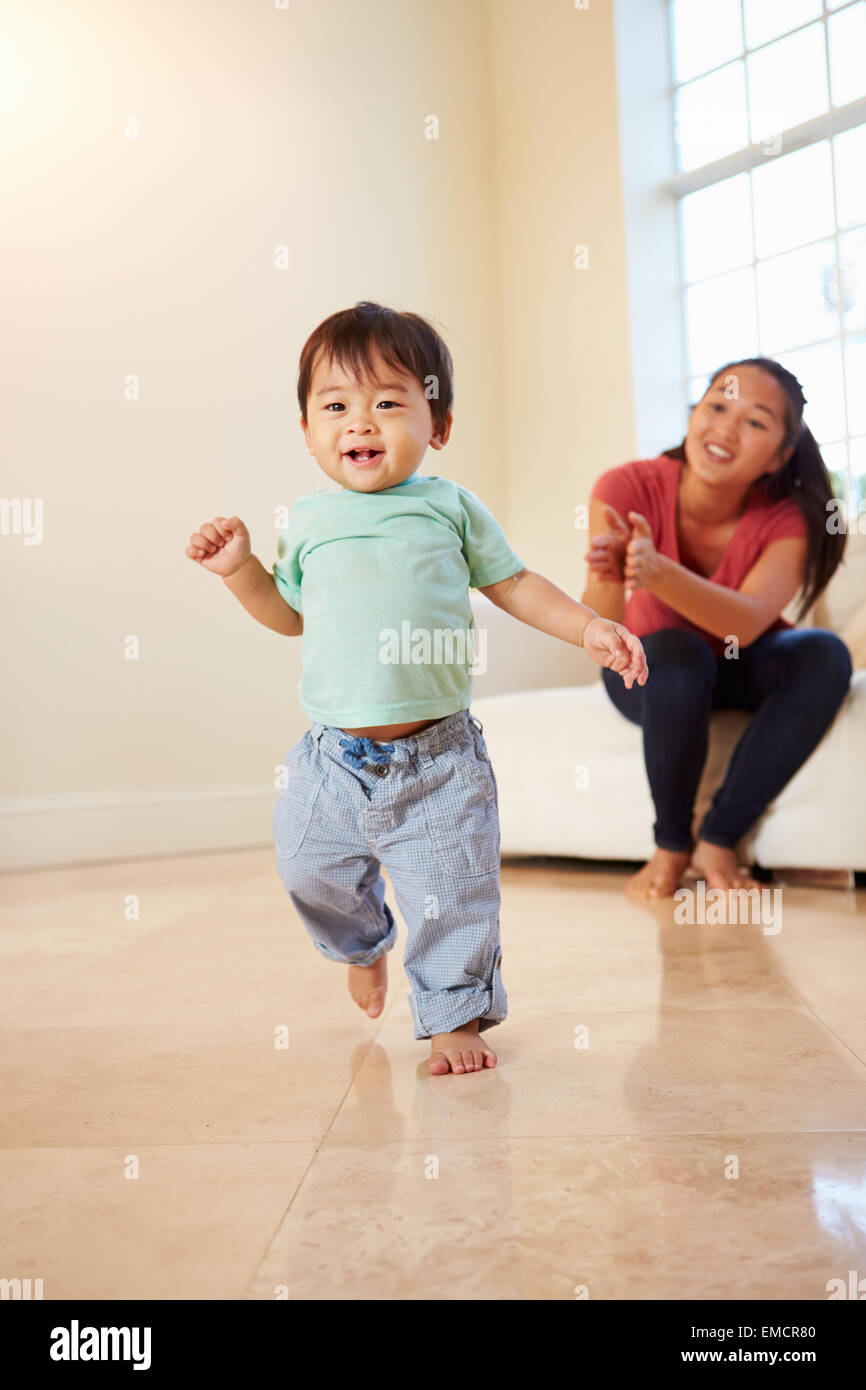 One Year Old Boy Taking First Steps With Mother Stock Photo