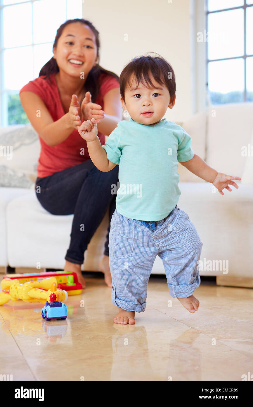 One Year Old Boy Taking First Steps With Mother Stock Photo