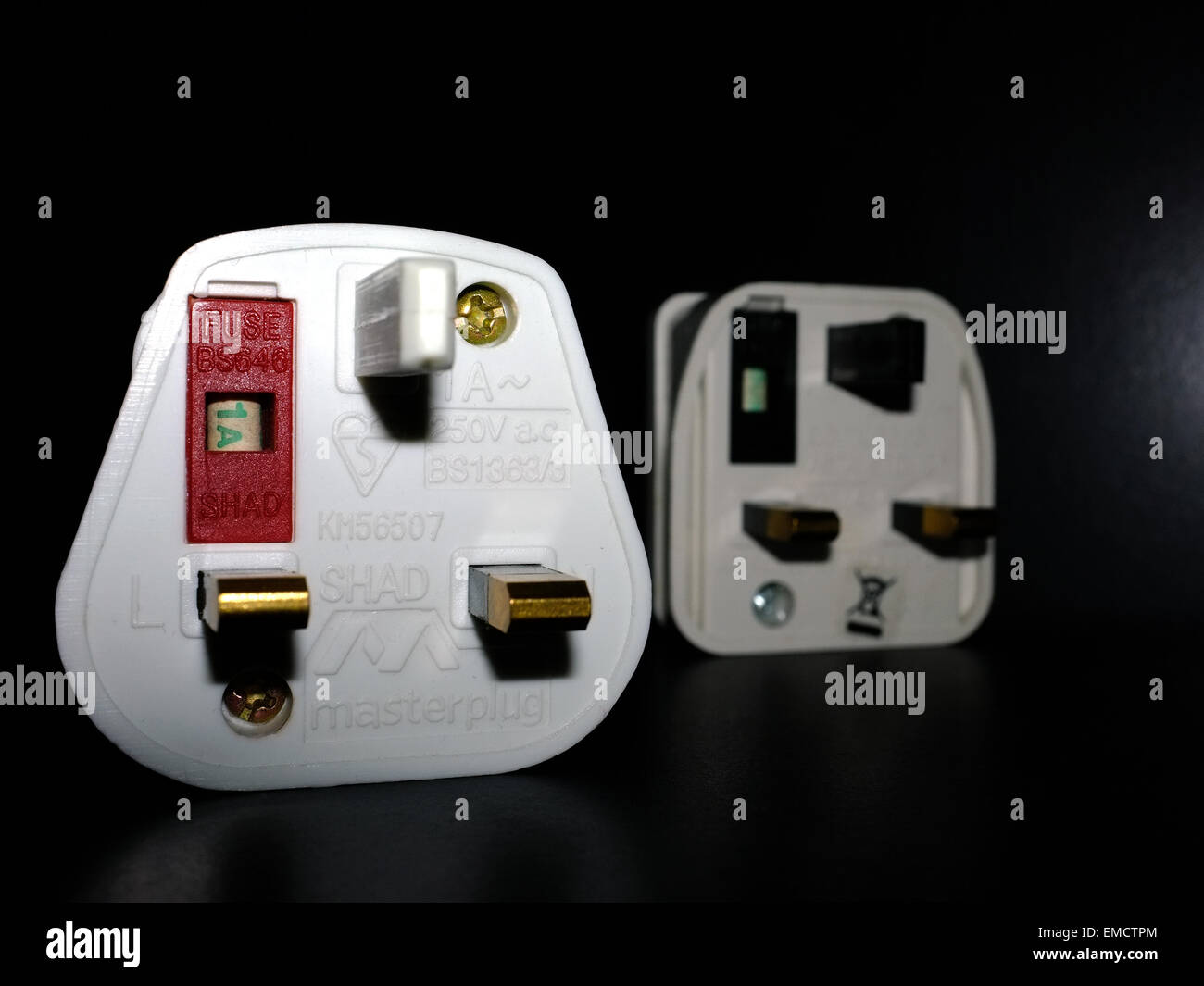 A British 3 pin electrical plug adapter photographed against a black