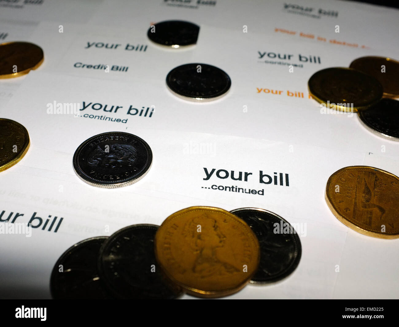 A pile of paper bills with coins on top of them. Stock Photo