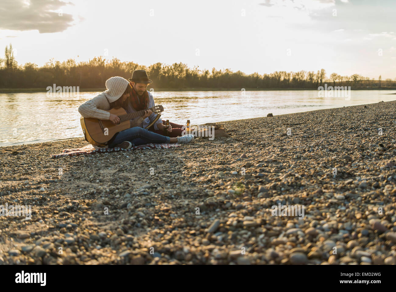 Couple at the riverside playing guitar Stock Photo - Alamy