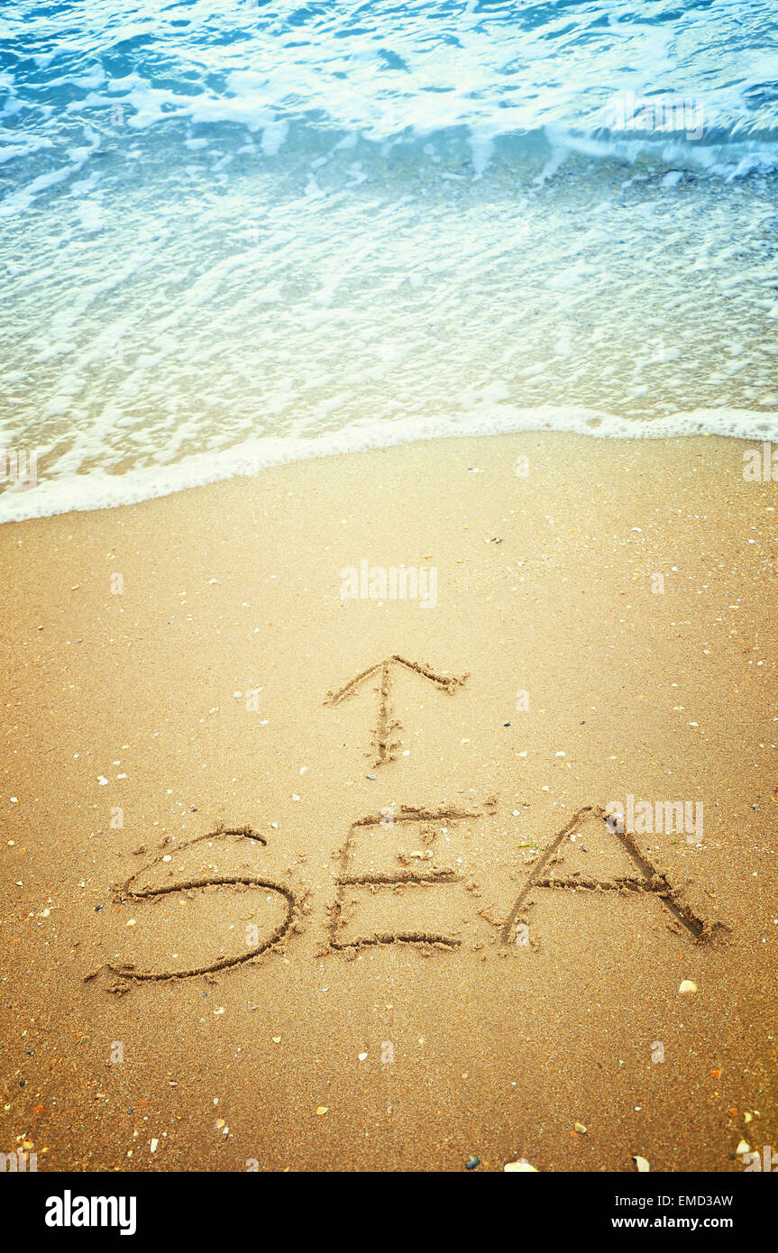 'Sea' and arrow written in the sand on the beach Stock Photo