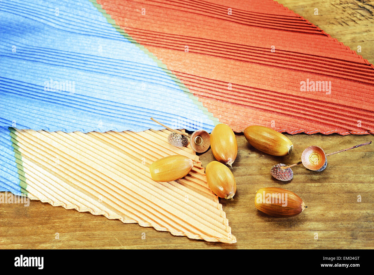 Pleated silk scarf and acorns on wooden surface Stock Photo