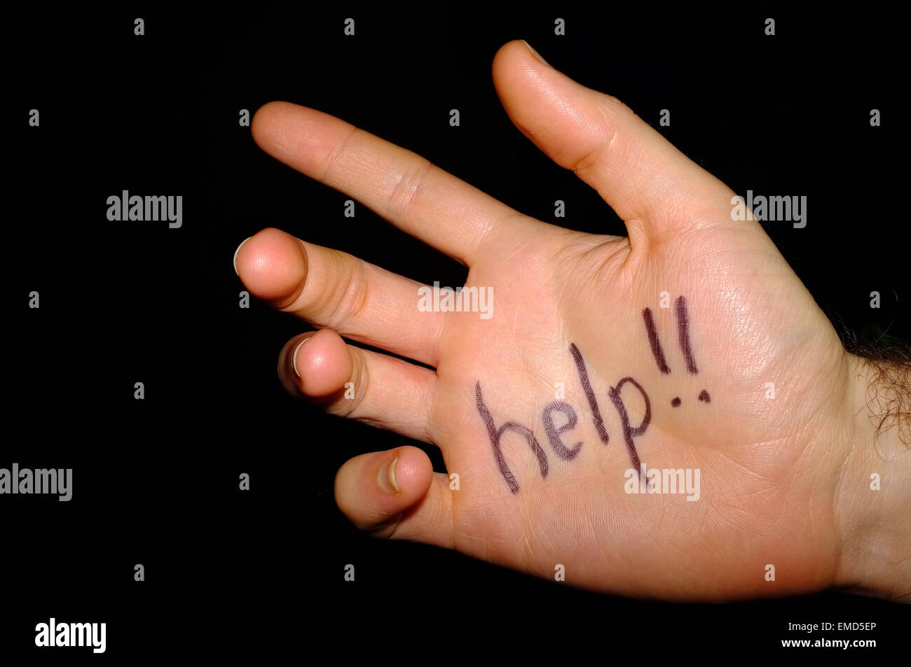 Help!! written on a white man's hand photographed against a black background. Stock Photo