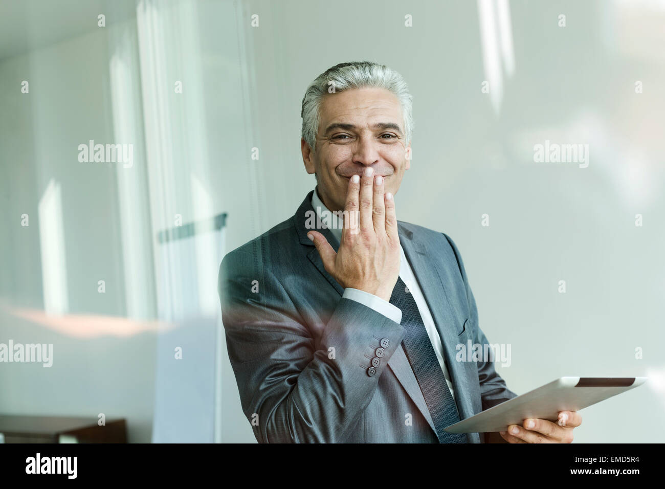 businessman-holding-digital-tablet-hand-on-mouth-giggling-EMD5R4.jpg