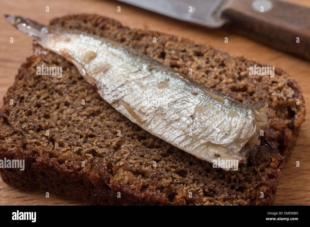 Piece of rye bread with sardine on the table with a knife Stock Photo
