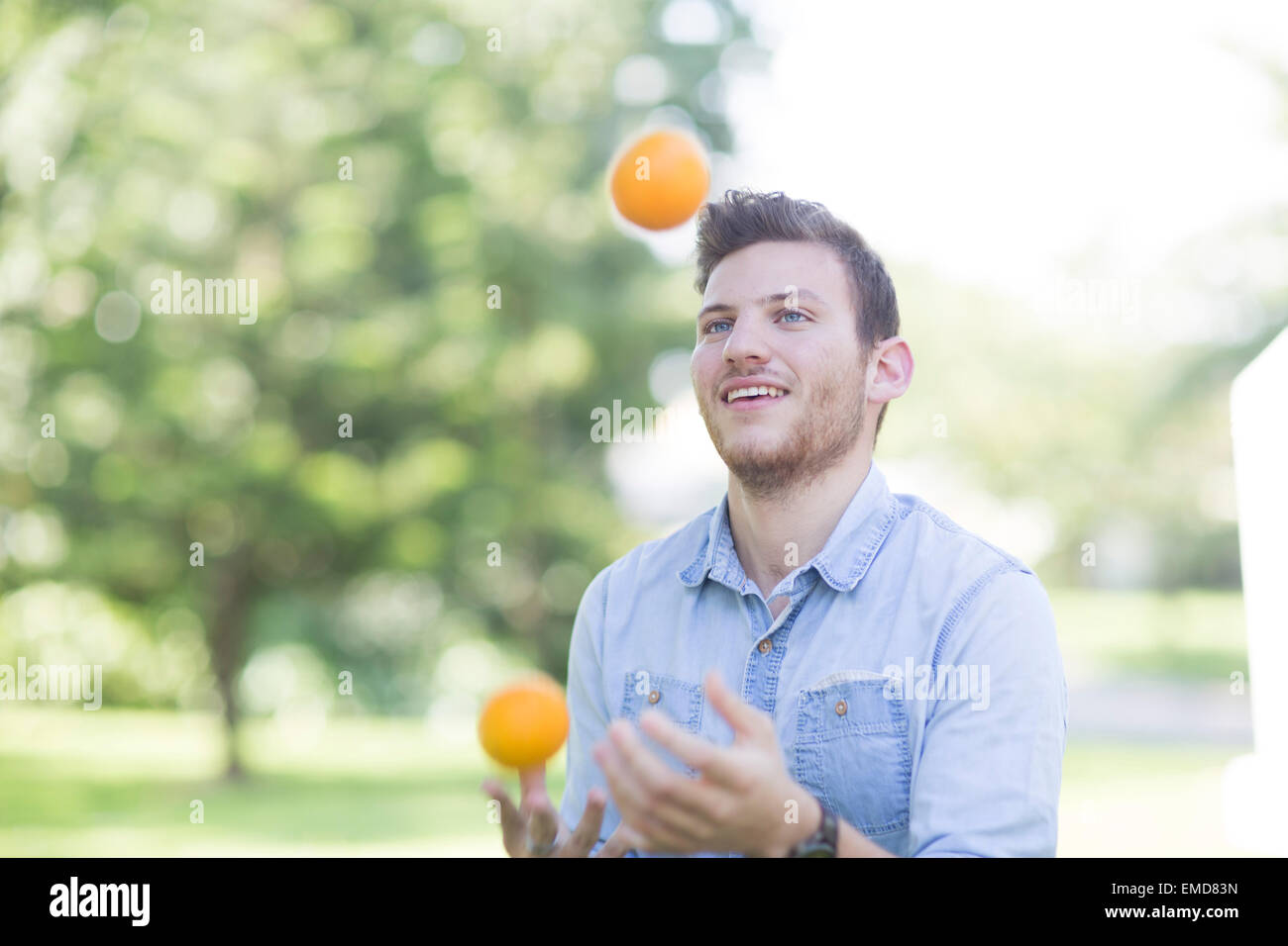 Young man juggling with oranges outdoors Stock Photo