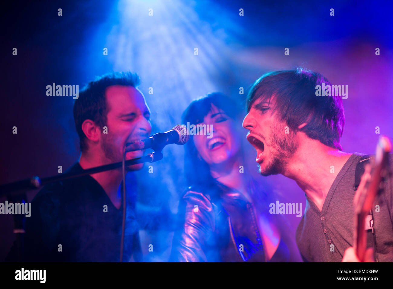 Rock band on stage screaming into microphone Stock Photo