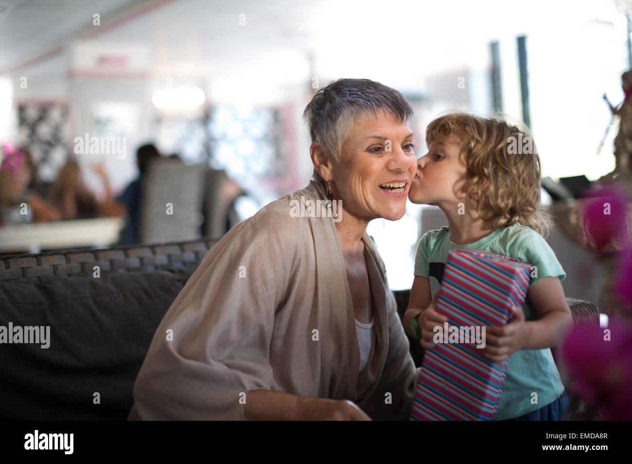 Grandmother getting a kiss from grandchild who received a gift Stock Photo