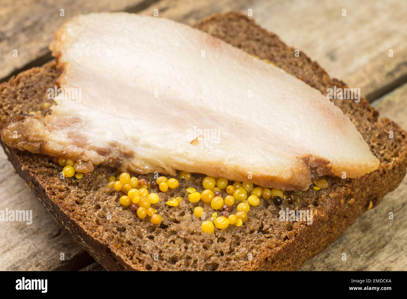 Close up image bacon sanwich with mustard on wooden table. Corned bacon on the bread Stock Photo
