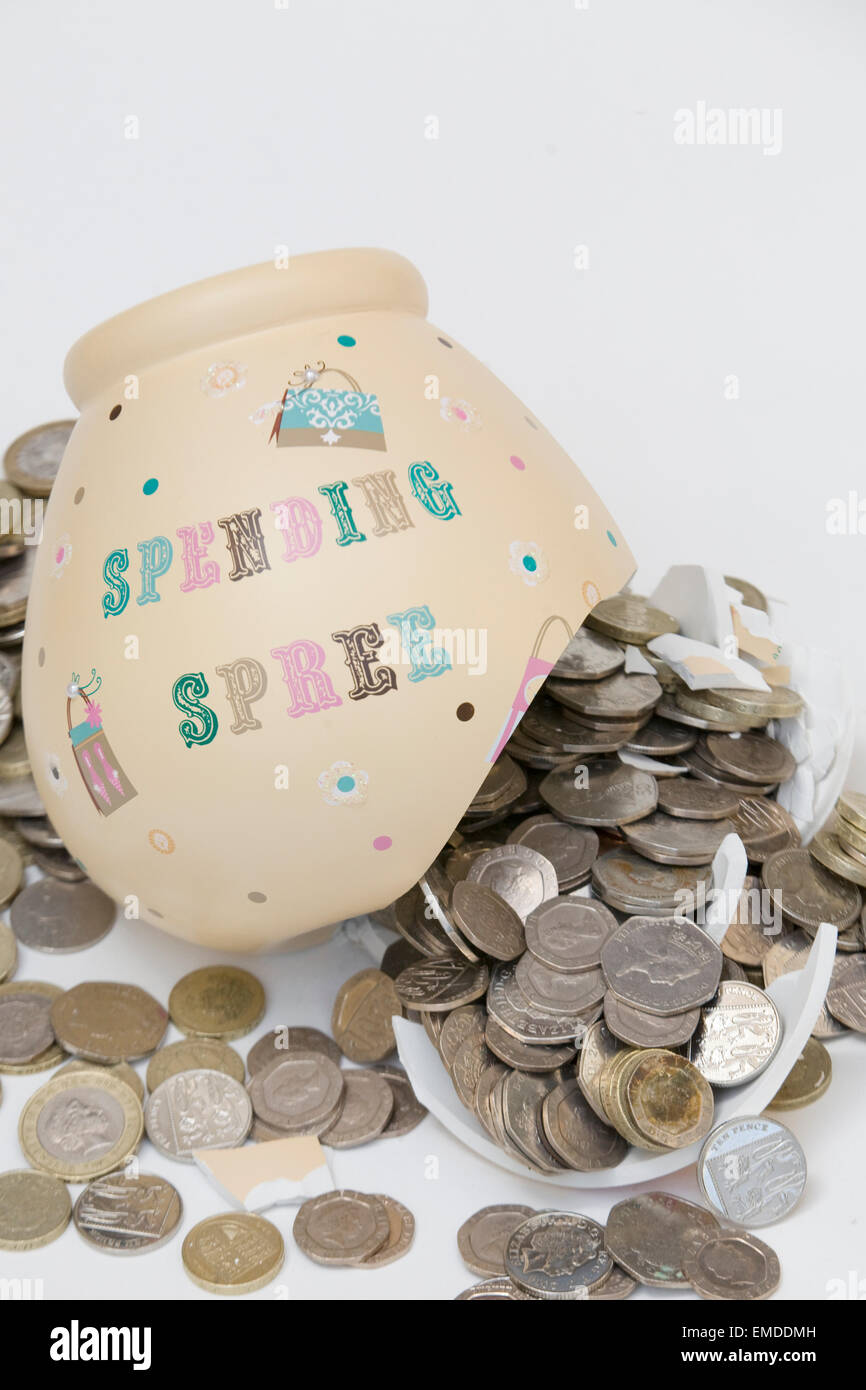 Smashed Money box with Coins pouring out of it on a white background Stock Photo