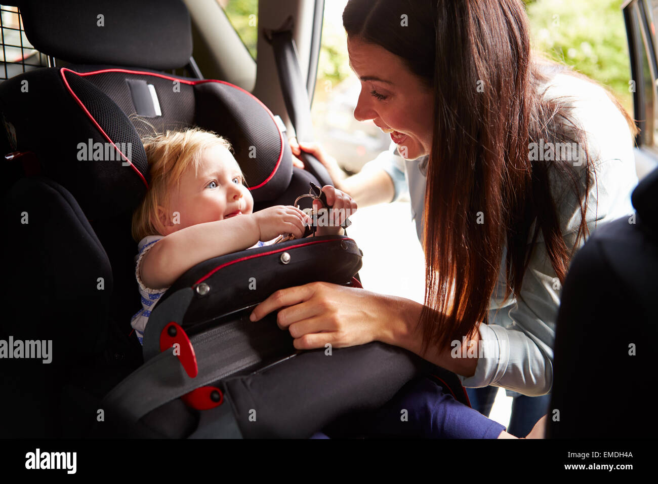 Mother Putting Daughter In Safety Seat On Car Journey Stock Photo Alamy