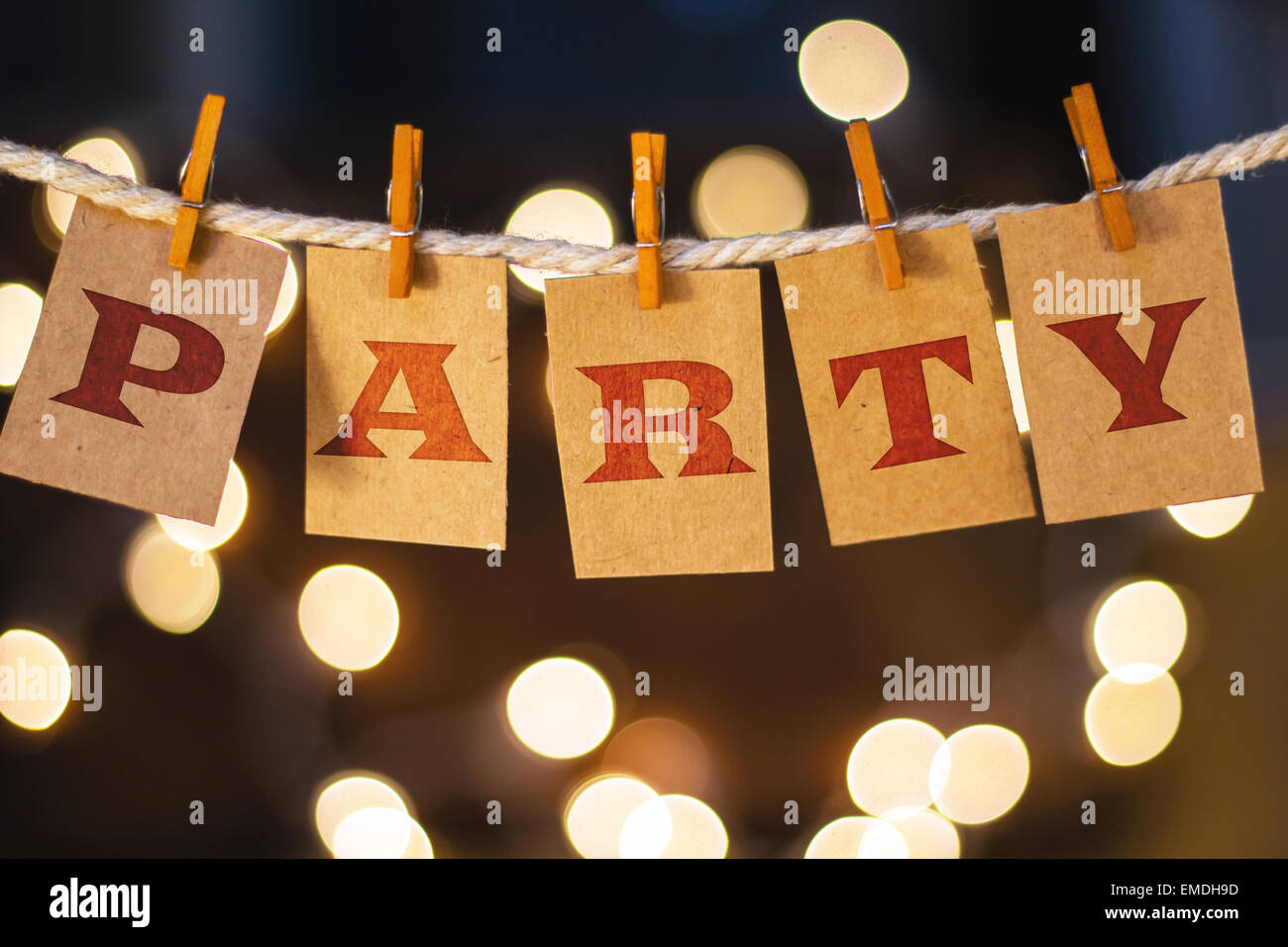 The word PARTY printed on clothespin clipped cards in front of defocused glowing lights. Stock Photo