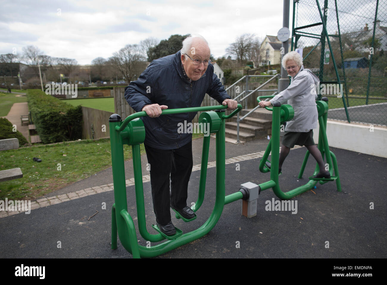 Elderly couple in their late 70's (her) and early 80's (him) exercising on outdoor fitness equipment, Kingsbridge, Devon, UK Stock Photo