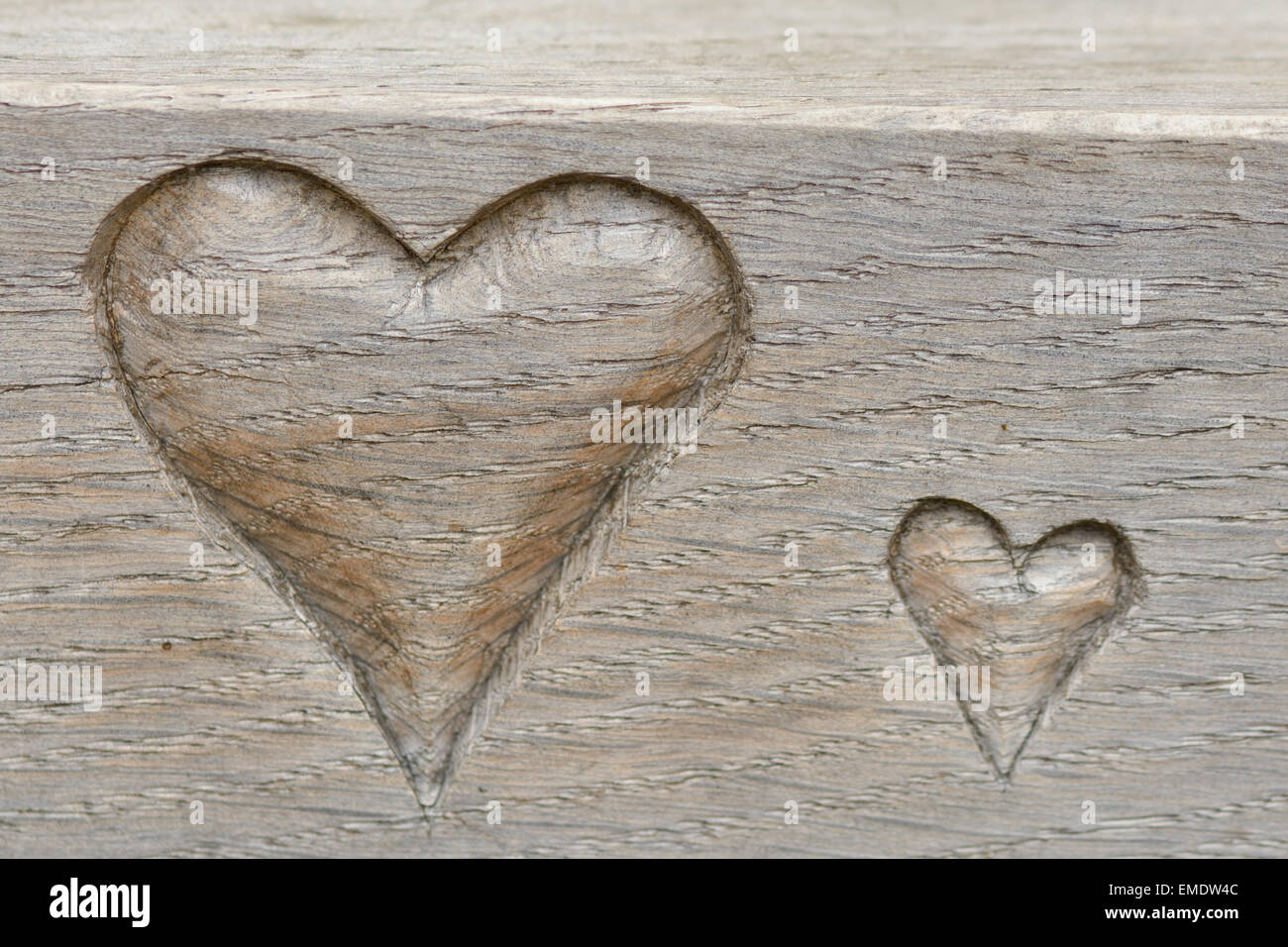Love hearts carved into edge of wooden bench Stock Photo