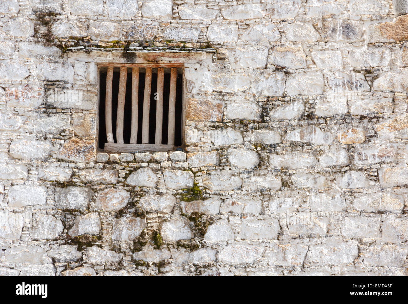 Old prison cell window with wooden bars in a white brick wall Stock Photo