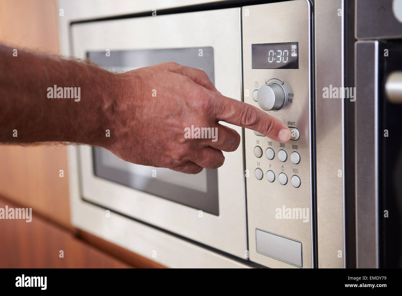 Close Up Of Hand Setting Timer On Microwave Oven Stock Photo