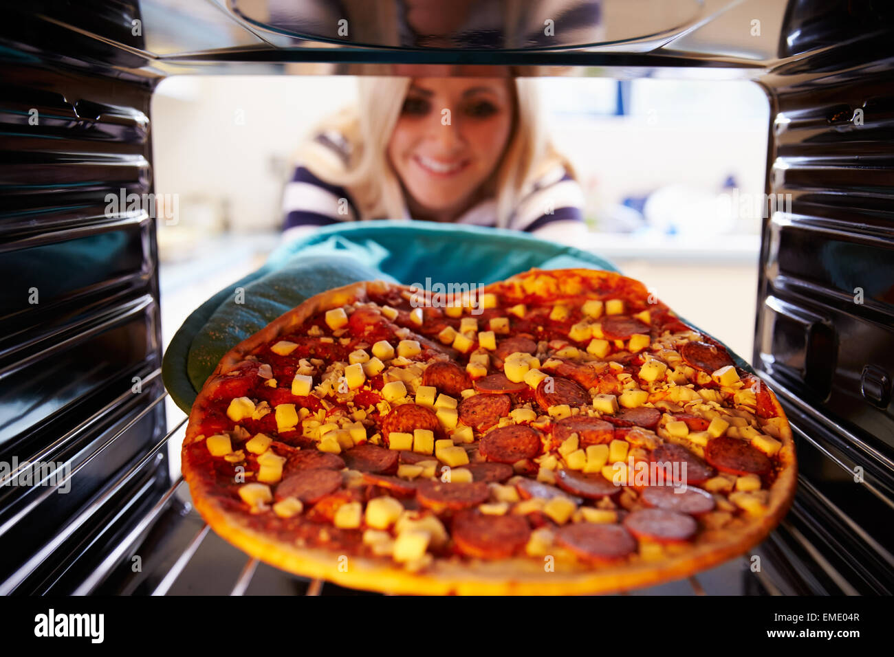 Woman Putting Pepperoni Pizza Into Oven To Cook Stock Photo Alamy