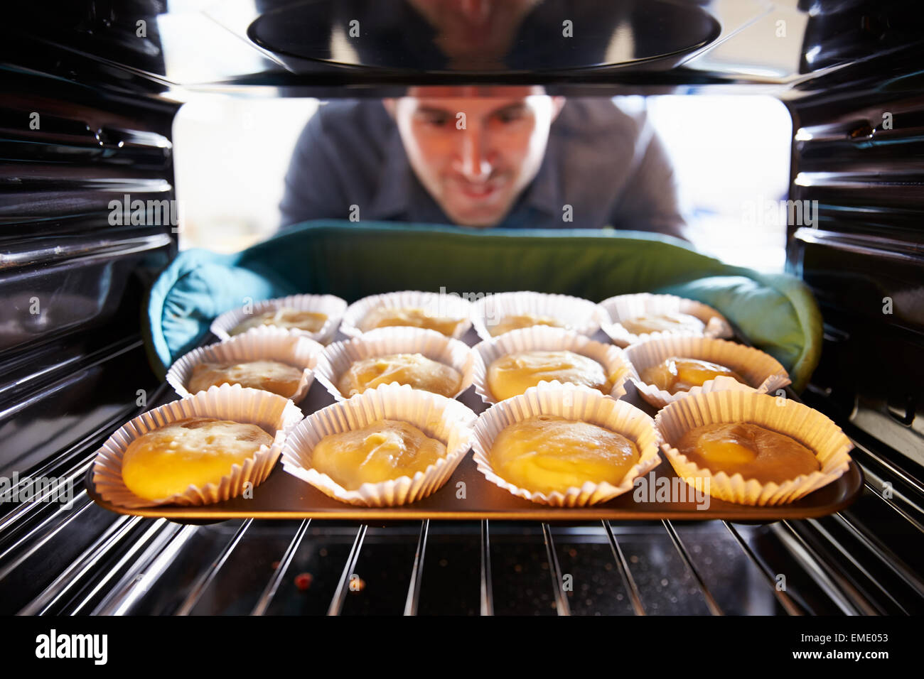 Man Putting Cupcakes Into Oven To Bake Stock Photo Alamy