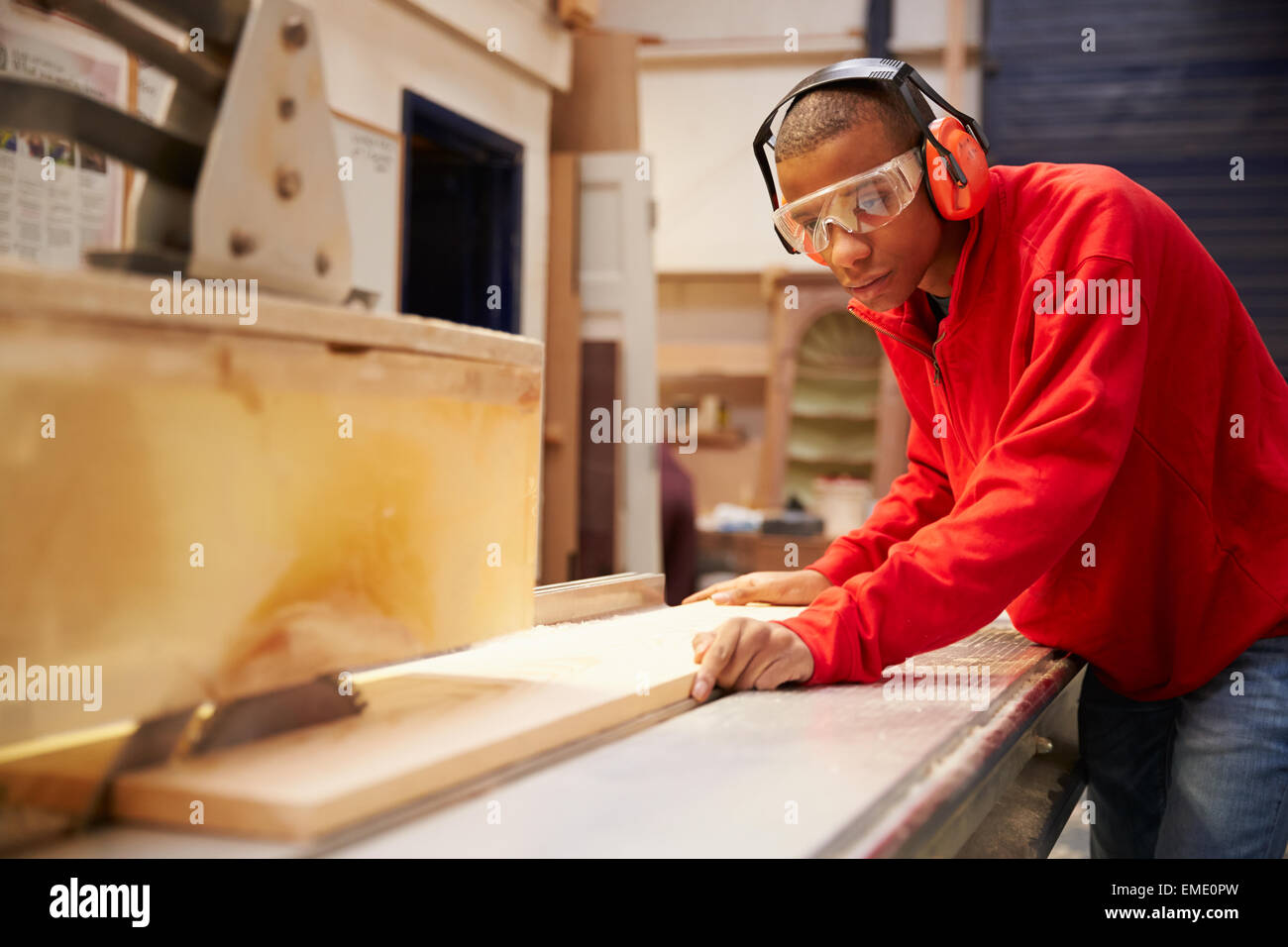 Apprentice Using Circular Saw In Carpentry Workshop Stock Photo