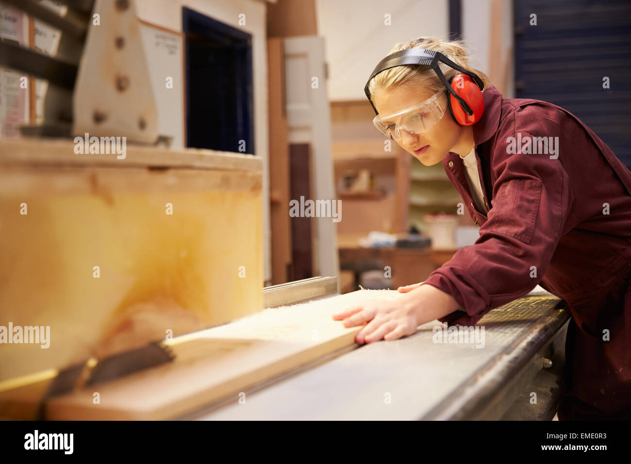 Female Apprentice Using Circular Saw In Carpentry Workshop Stock Photo