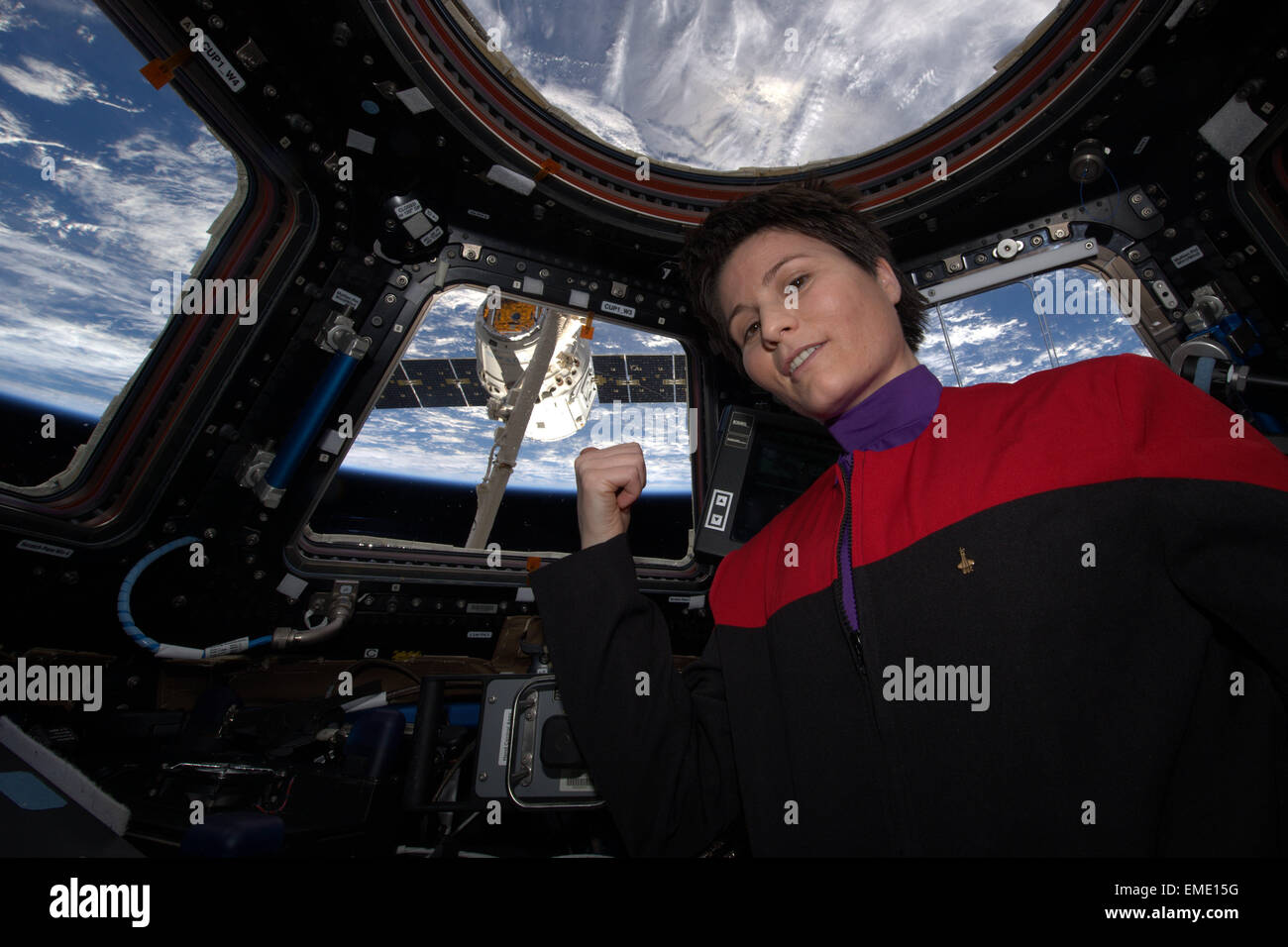 International Space Station Expedition 42 European Space Agency Astronaut Samantha Cristoforetti points to the SpaceX Dragon capsule after grabbing the spacecraft using the Canadarm robotic arm from inside the copula April 17, 2015 in Earth Orbit. Stock Photo