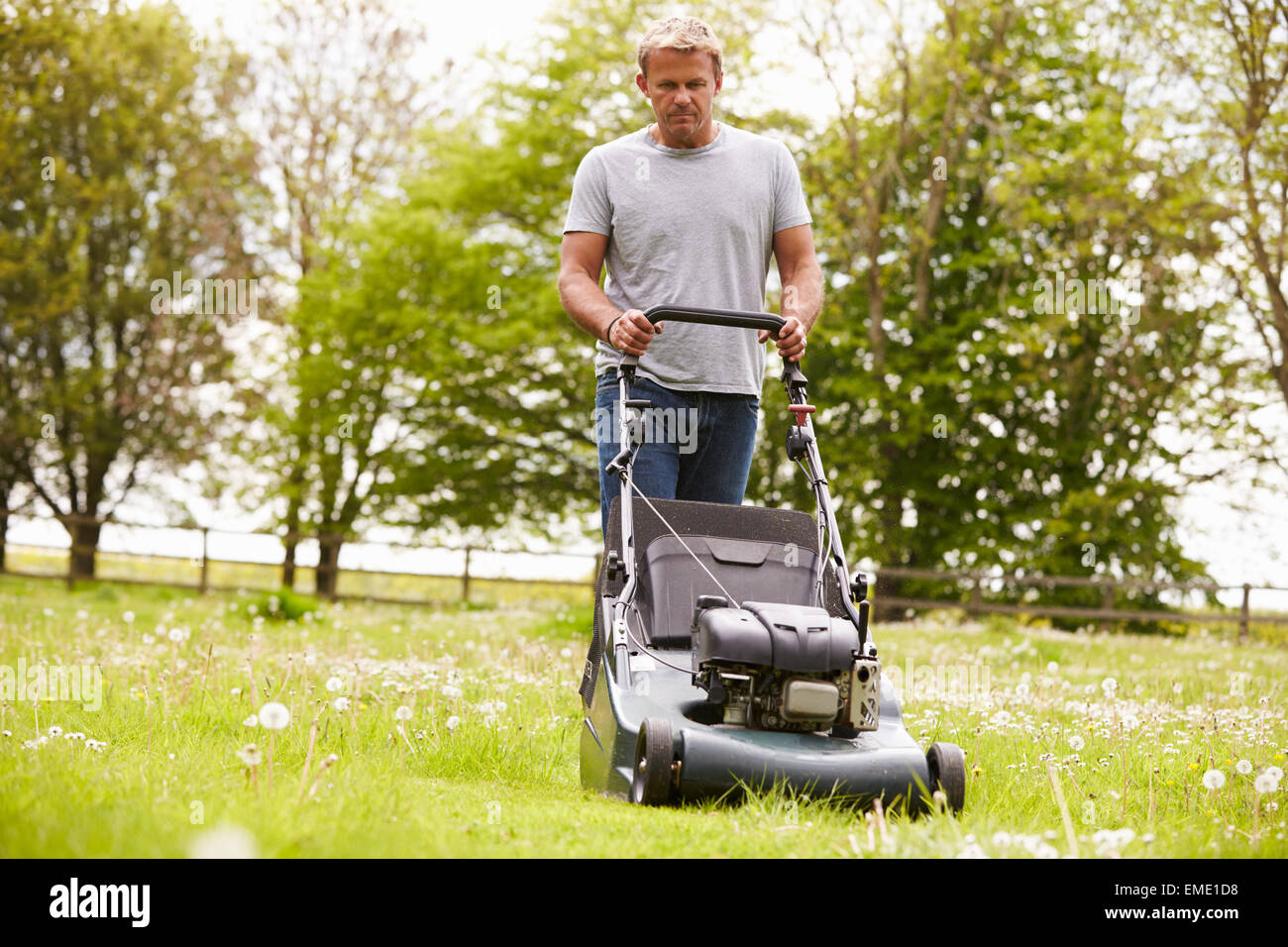 Man Working In Garden Cutting Grass With Lawn Mower Stock Photo Alamy