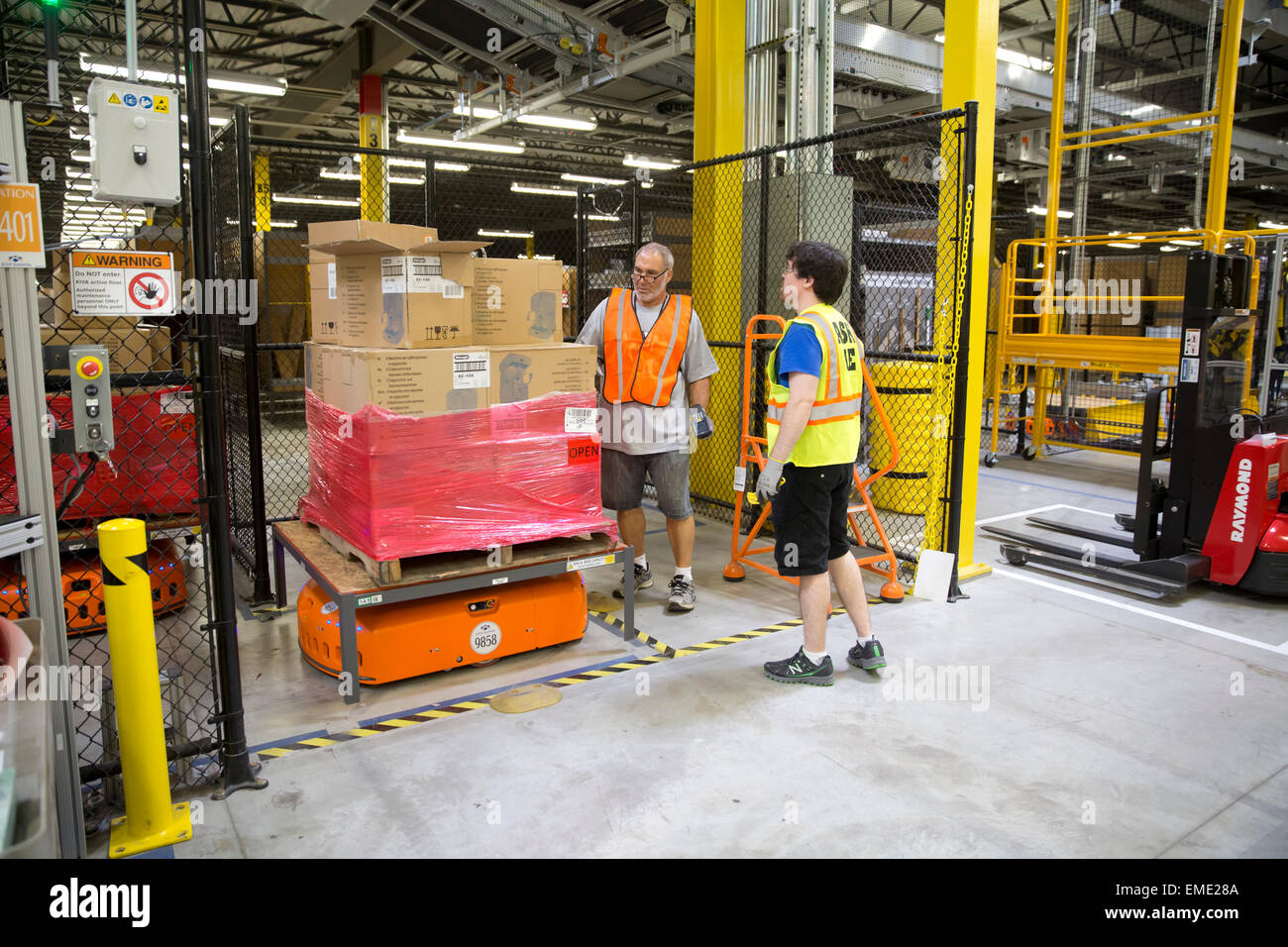 Amazon.com employees scan barcodes on pallet with packages in warehouse Stock Photo