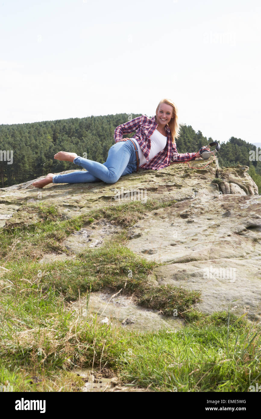 Teenage Girl Relaxing On Rocks Outdoors Stock Photo
