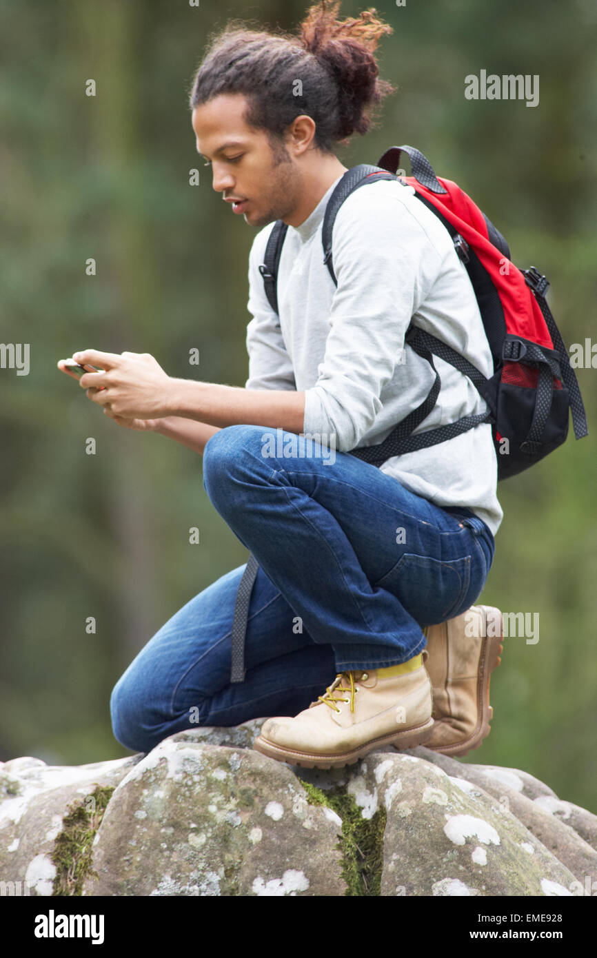 Man Using Mobile Phone Whilst Hiking In Countryside Stock Photo