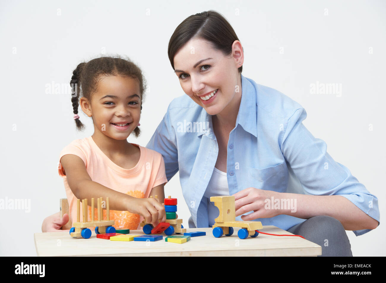Teacher And Pre-School Pupil Playing With Wooden House Stock Photo
