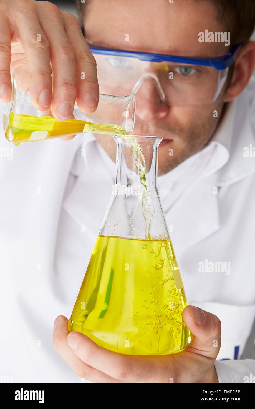 Scientist Pouring Liquid From Test Tube Into Flask Stock Photo