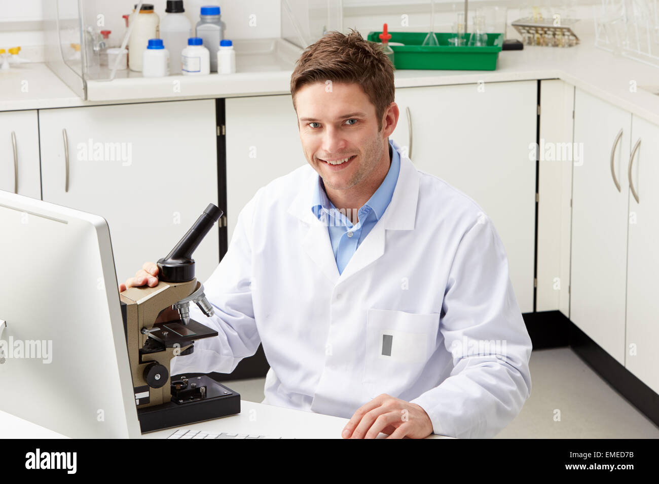Portrait Of Scientist With Microscope In Laboratory Stock Photo