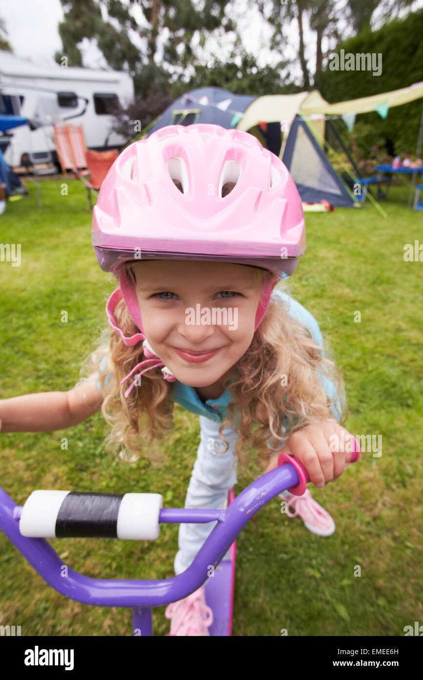 Girl Riding Scooter Whilst On Family Camping Holiday Stock Photo